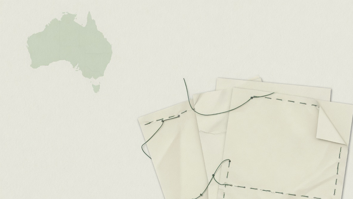A pale map of Australia beside stitched blank papers.